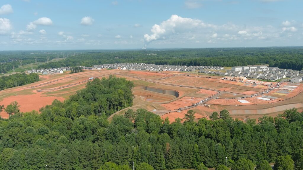 a birds-eye view of a job site with houses in the distance