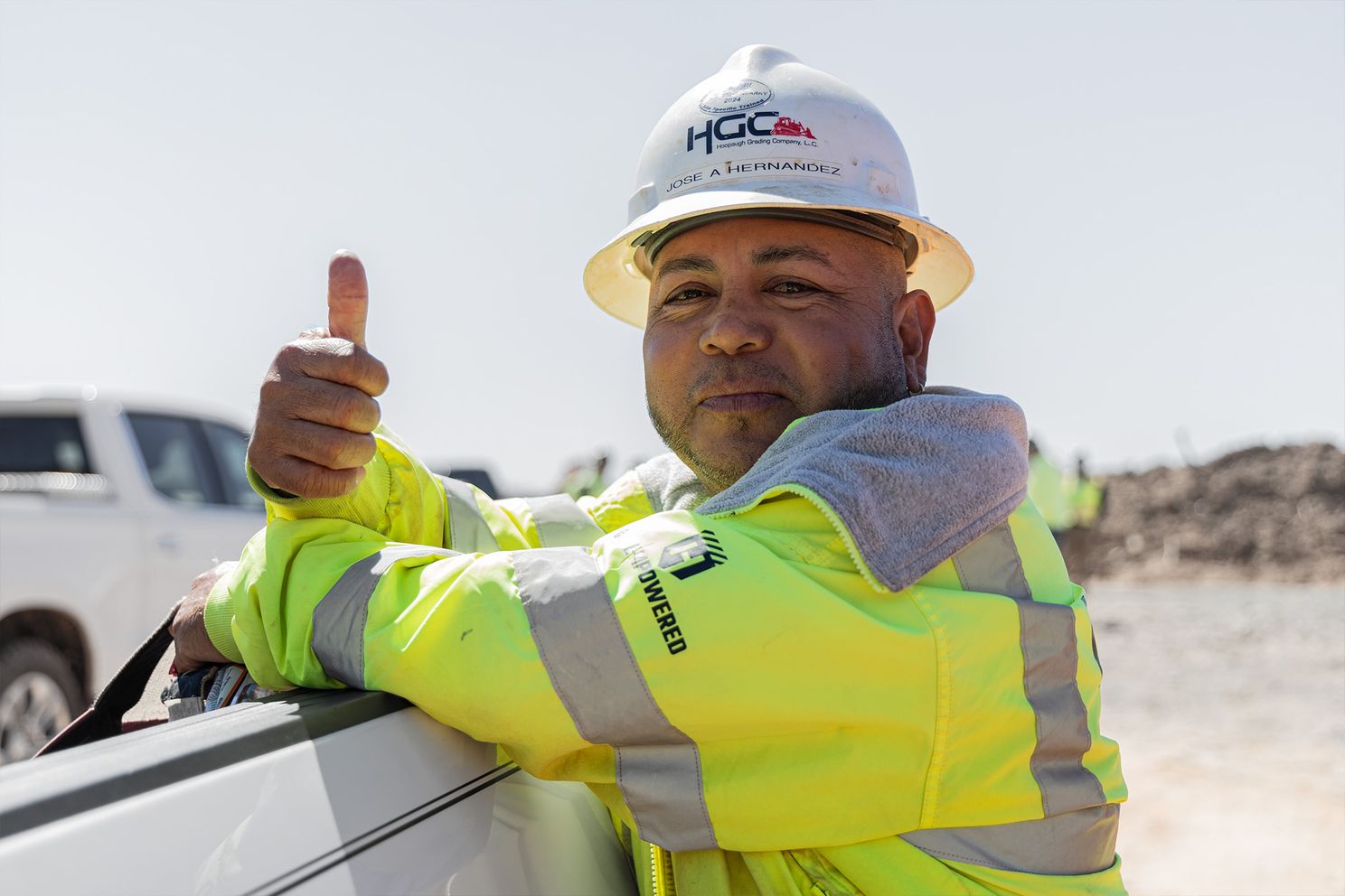 HGC employee smiling on worksite with a thumbs up.