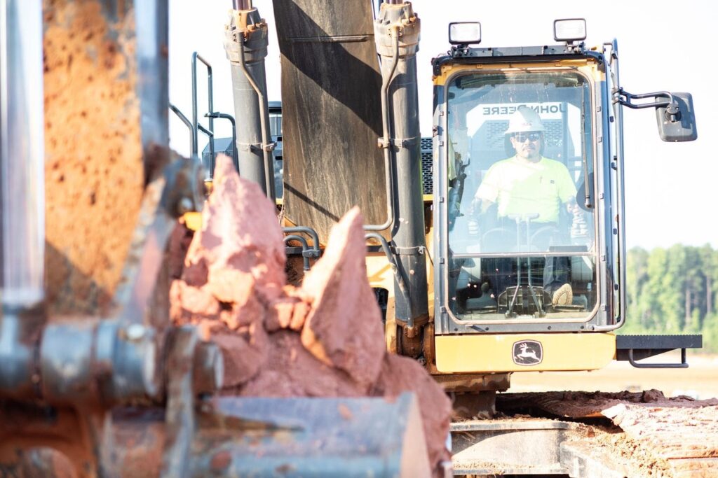 a man driving a piece of a equipment on a dirt job site